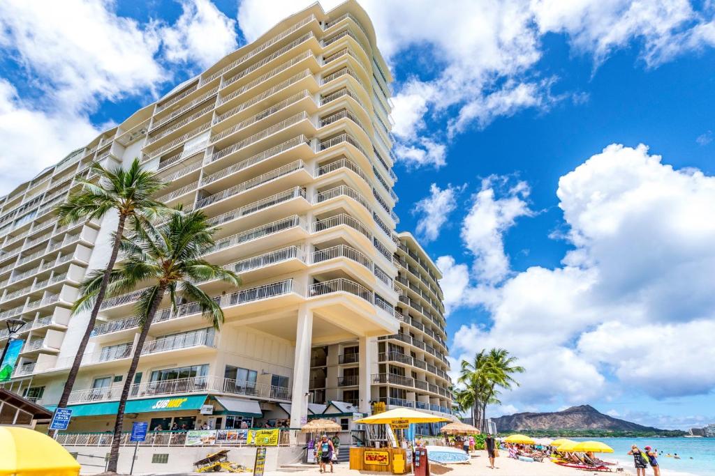 檀香山Waikiki Shore 1116 Beachfront的棕榈树海滩上的一座大建筑
