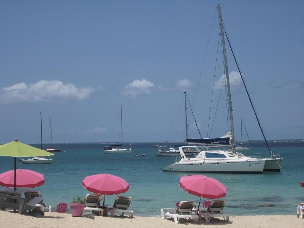 马里戈特Studio Chic Saint-Martin的海滩上的一组椅子和遮阳伞,有船