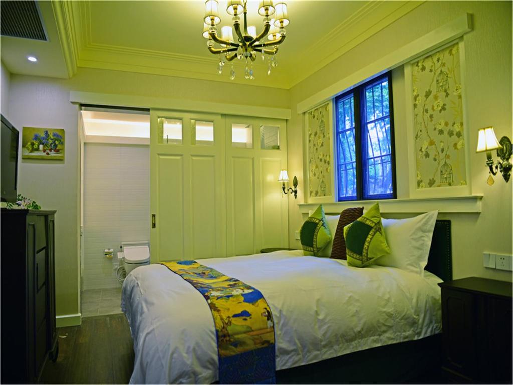 上海苏荷精选花园别墅酒店（上海淮海路店）的一间卧室配有一张带吊灯和窗户的床。