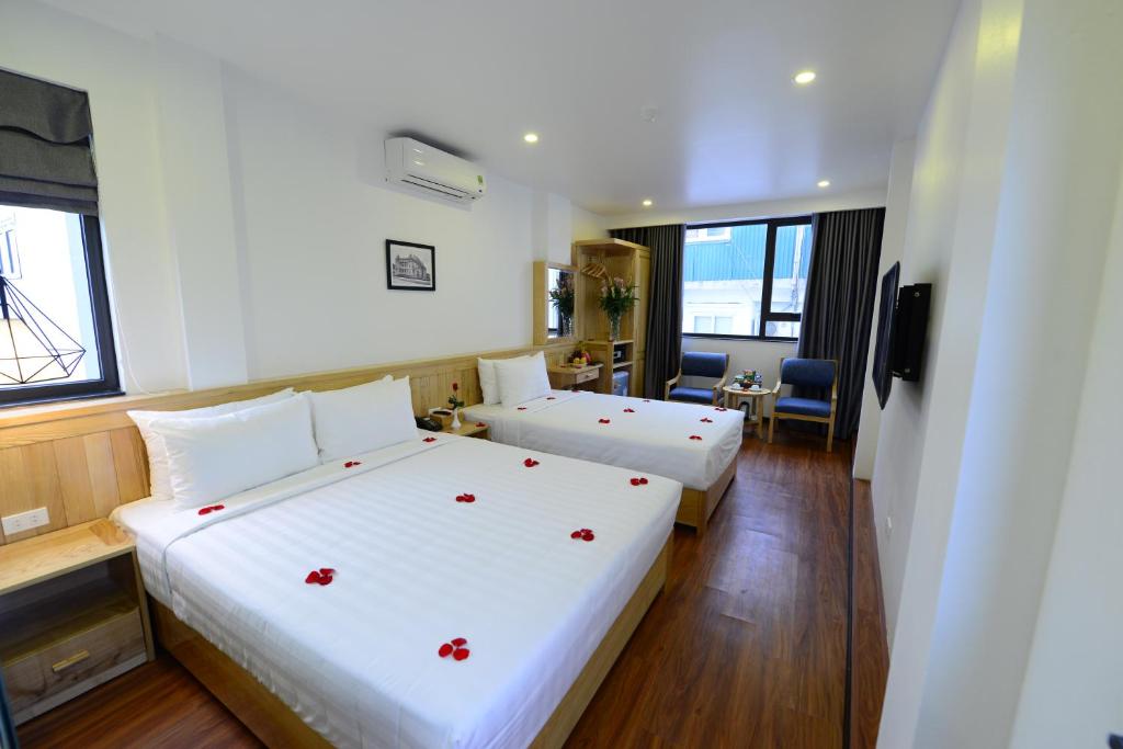 河内Blue Hanoi Inn Luxury Hotel的酒店客房,配有两张带红色鲜花的床。