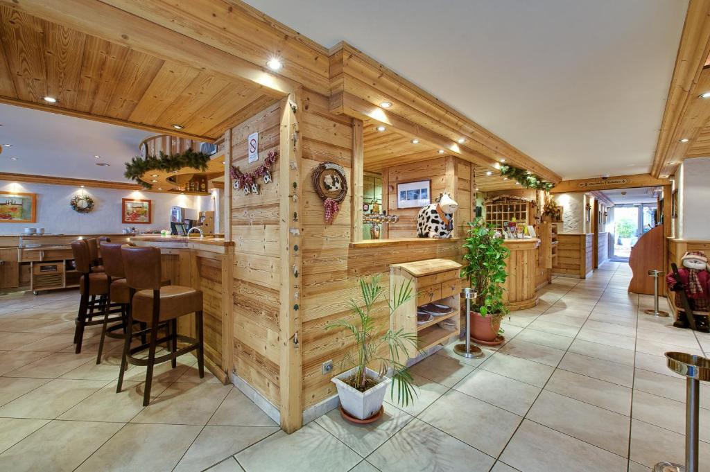 托讷Hotel Du Commerce的一间带木墙的厨房和一间带凳子的酒吧