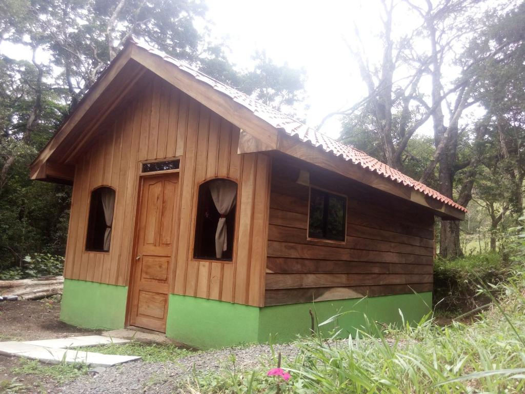 蒙泰韦尔德哥斯达黎加Monteverde Romantic Cottage的田野上有一扇门的小木房子