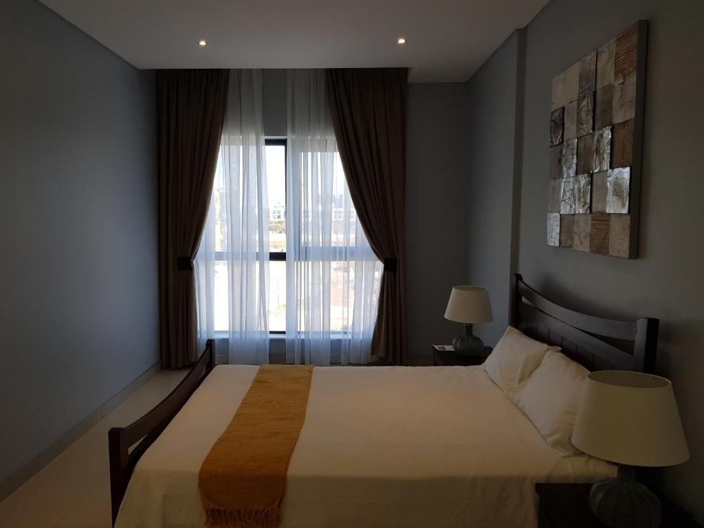 哈博罗内Apartments at Itowers, CBD, Gaborone的一间卧室设有一张大床和一个窗户。