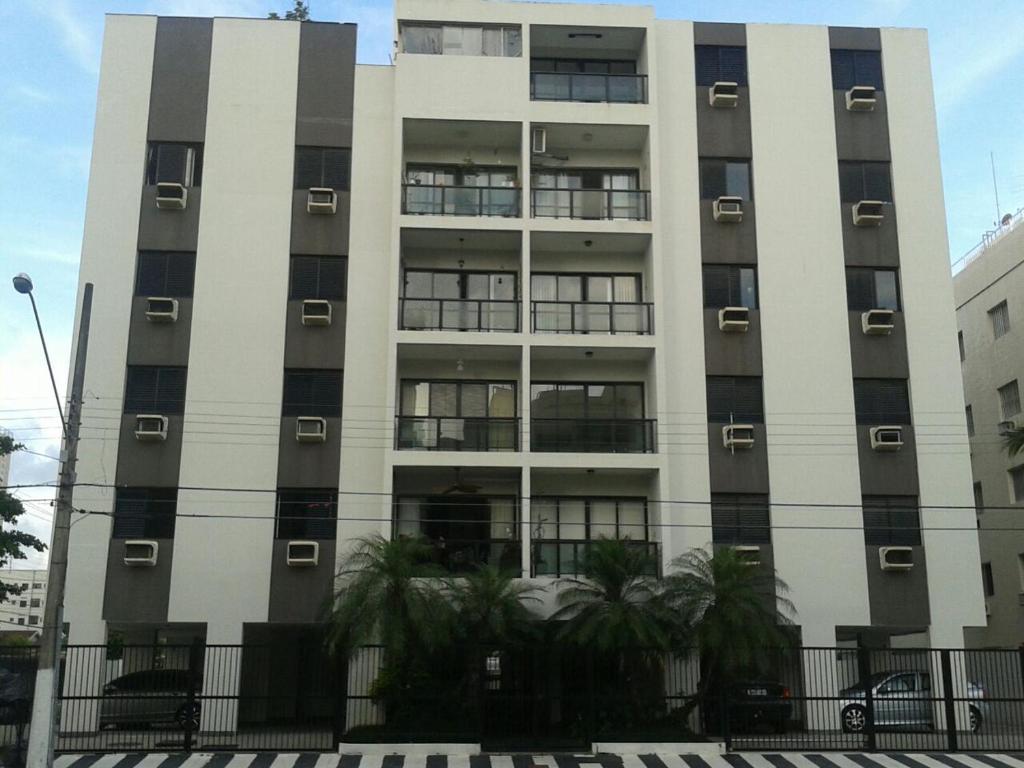 瓜鲁雅Apartamento Guarujá的一座高大的建筑,前面有窗户和棕榈树