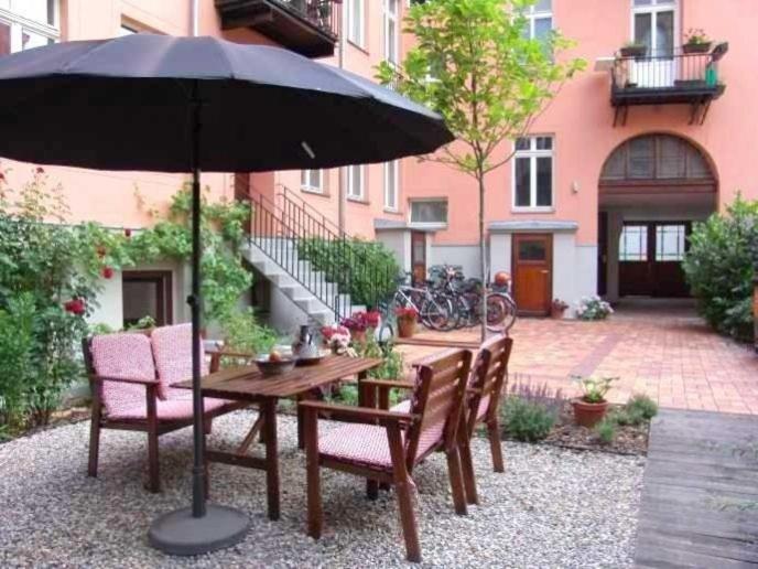 柏林Berlin Apartments Mitte的一张带椅子的木桌和一把伞