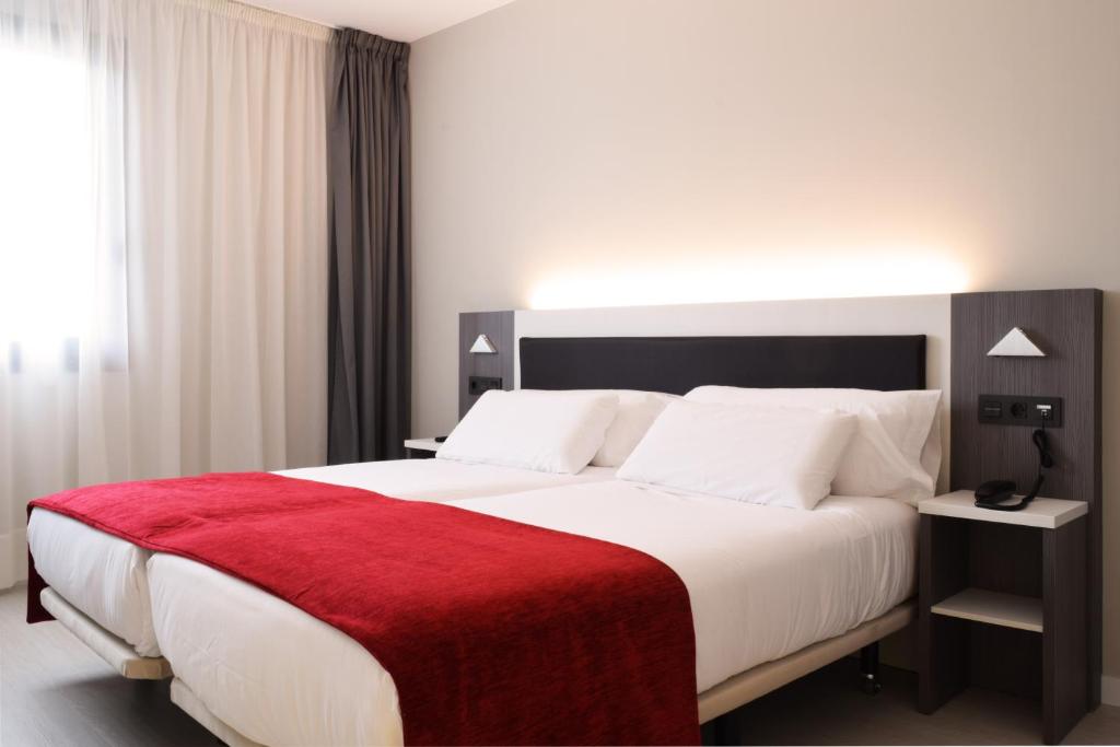 德里奥新毕尔巴鄂机场酒店的一间卧室配有一张带红色毯子的大床