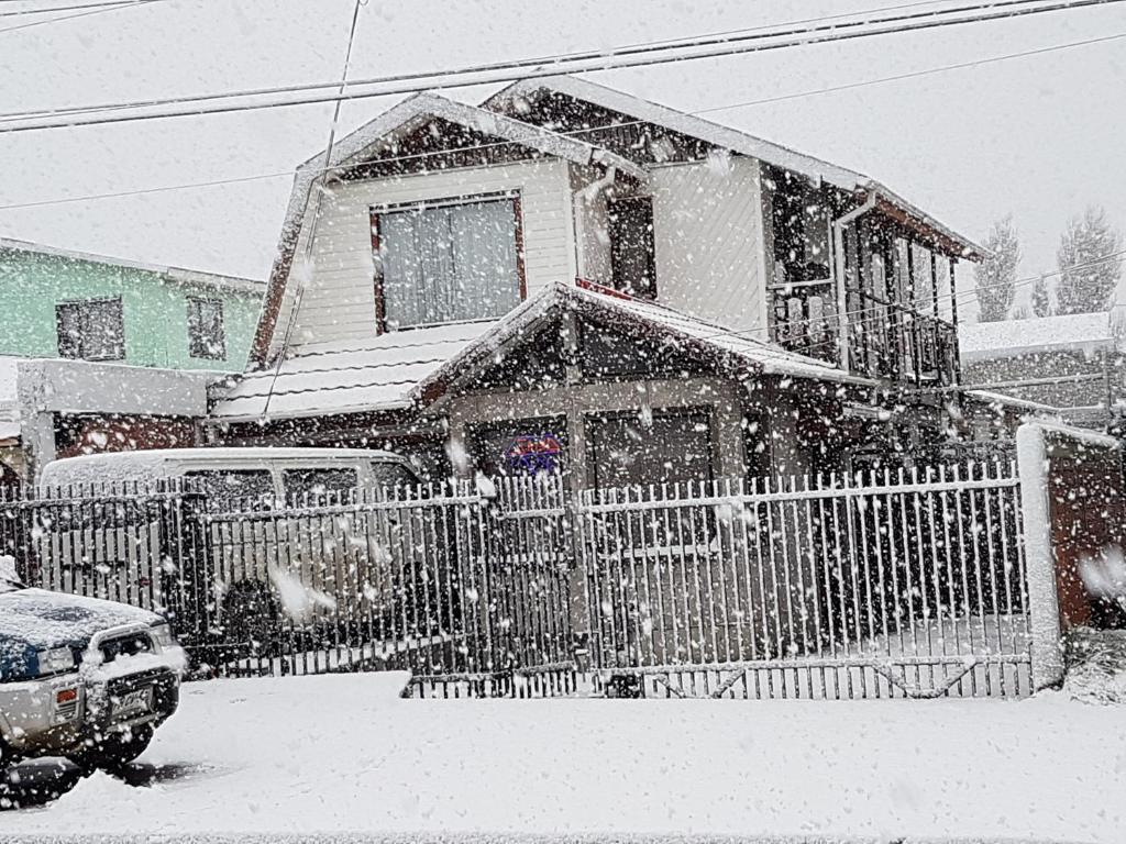 蓬塔阿雷纳斯La Casa Guesthouse的雪中带围栏的房子