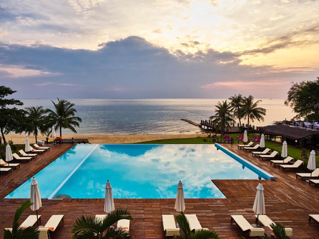 富国富国岛盛泰乐精选晨曦水疗及度假村的一个带椅子的游泳池,背景是大海