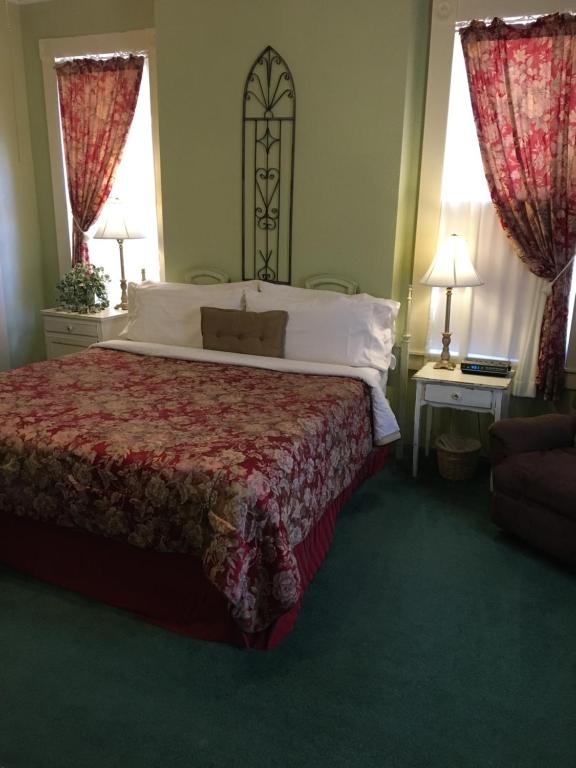 Fort ScottThe Courtland Hotel & Spa的一间卧室设有一张大床和两个窗户。