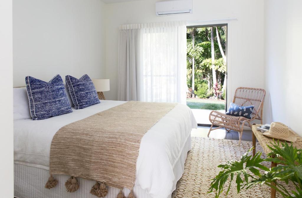 拜伦湾Satara Byron Bay - Adults Only的一间卧室配有一张带蓝色枕头的床和一扇窗户。