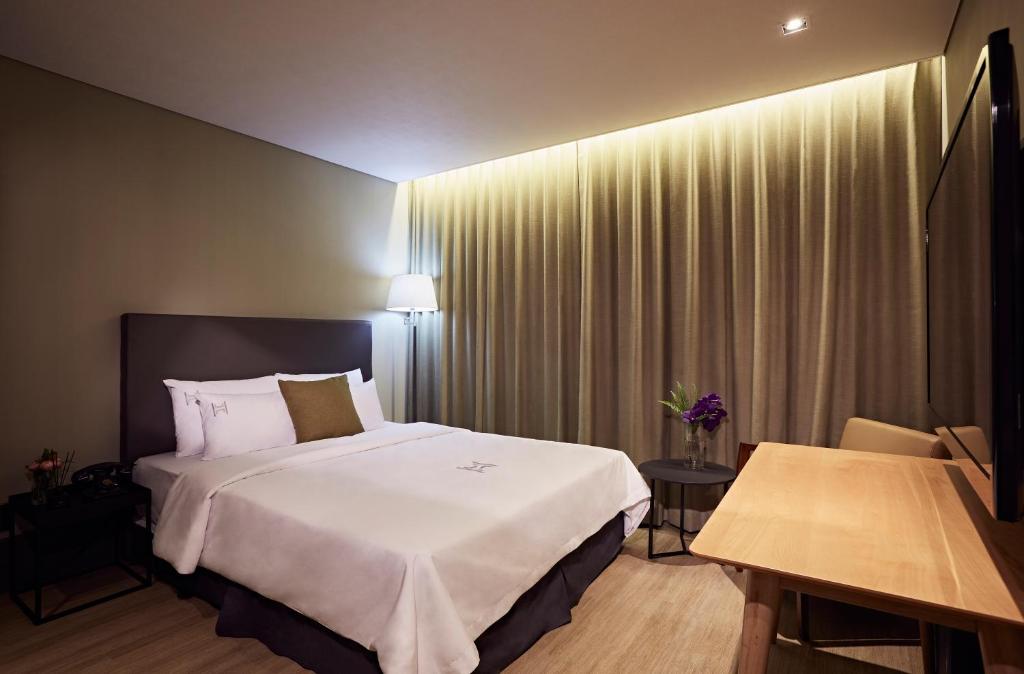 城南市黑拉西斯酒店的酒店客房设有一张大床和一张桌子。