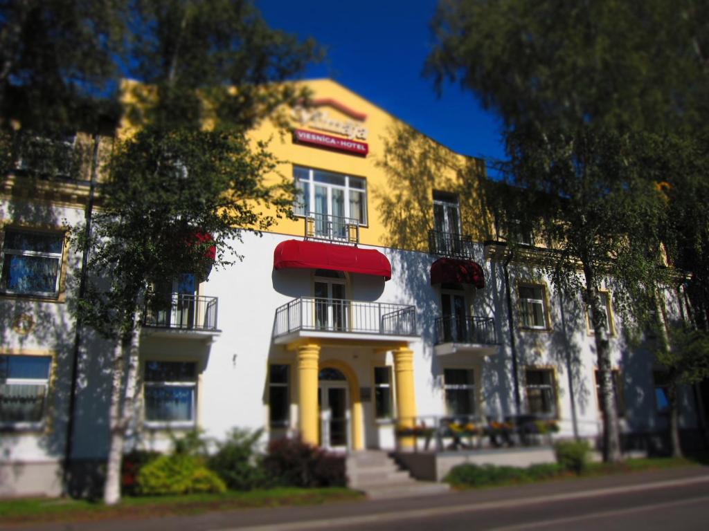 里加威玛加酒店的黄色和白色的建筑,有红色遮阳篷