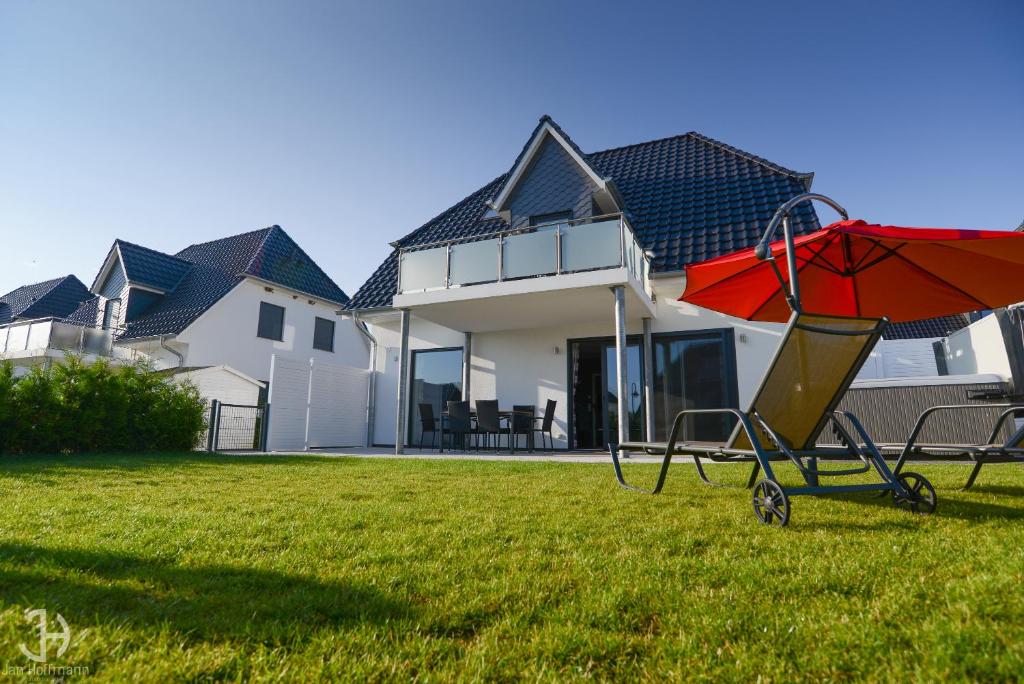 格赫伦-莱宾Villa Fleesenstrand的坐在房子前面的草上的一个红伞