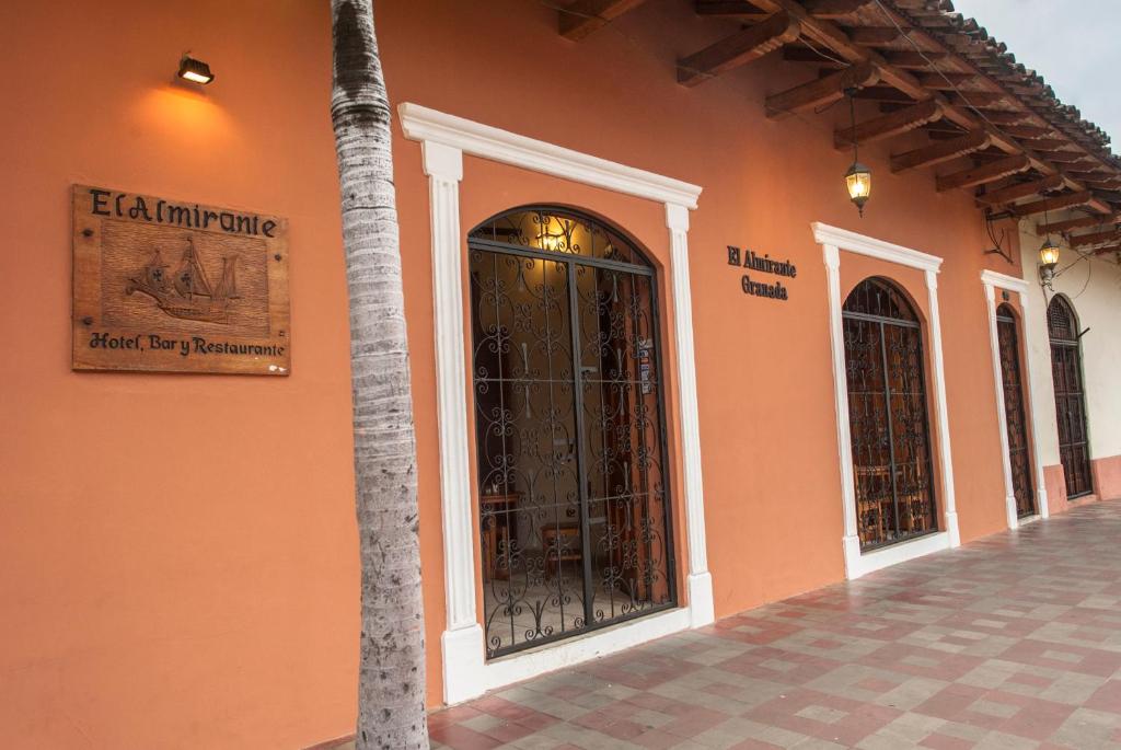 格拉纳达海军上将酒店的一座橙色的建筑,有门和棕榈树