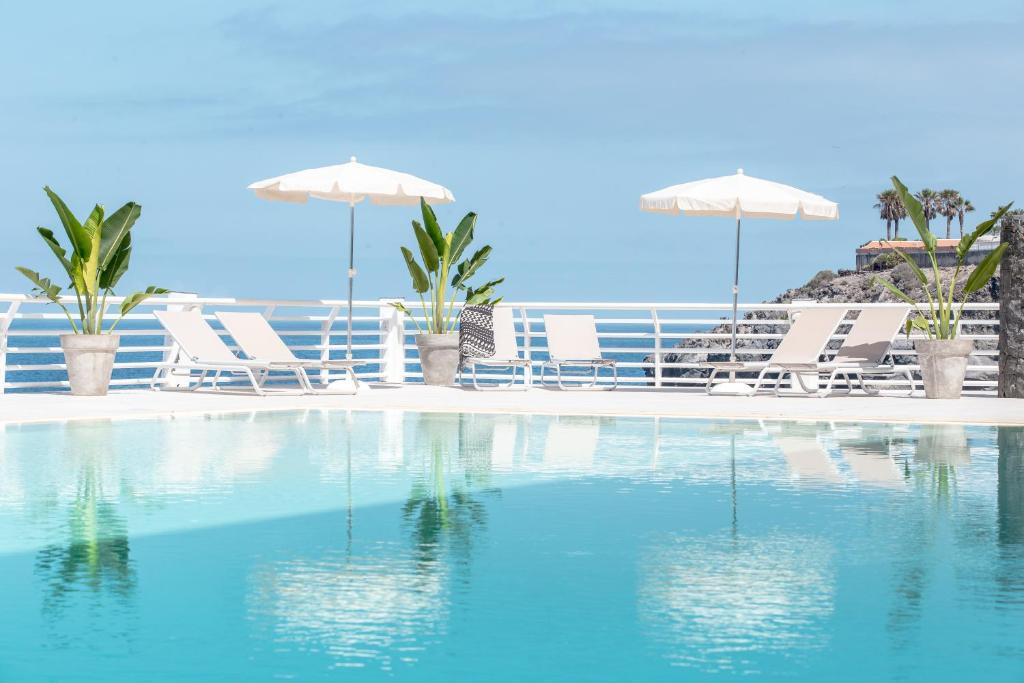 卡亚俄萨尔瓦赫大西洋假日酒店的海滩上带椅子和遮阳伞的游泳池