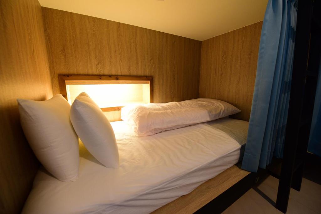 台东二高轻旅 K2 Hostel 的一间卧室配有带枕头和灯的床