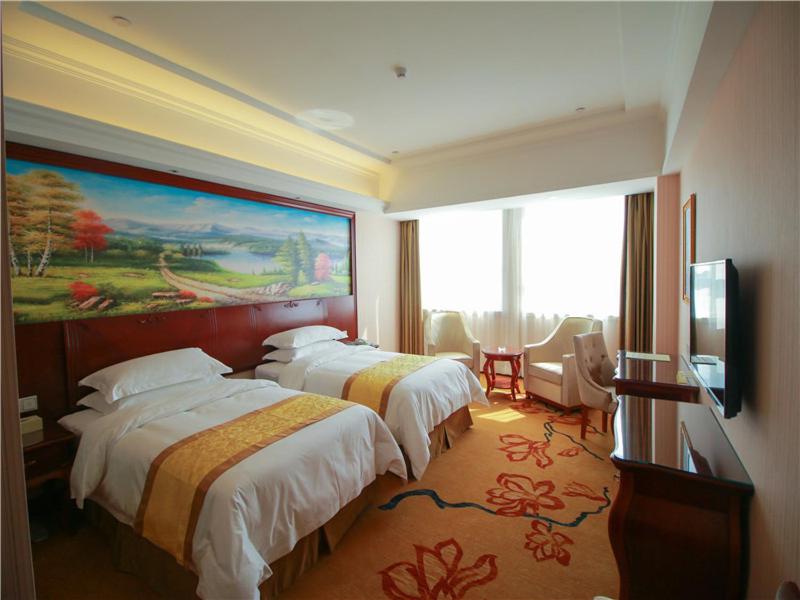 荣成维也纳国际酒店山东威海荣成店的酒店客房设有两张床,墙上挂有绘画作品