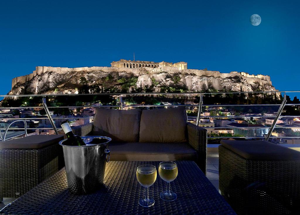 雅典普拉卡酒店的阳台上的桌子和两杯葡萄酒