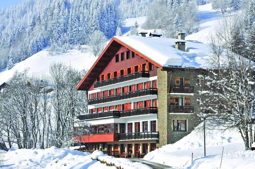 梅杰夫普拉利安德小屋蓝色假日酒店的雪中一座大建筑,有雪覆盖的树木