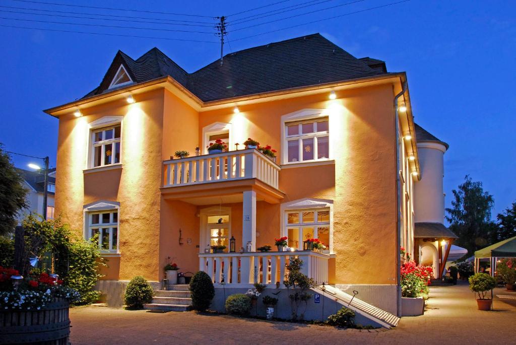 尼特尔Weingut und Gästehaus Apel的黄色的大房子,晚上设有阳台