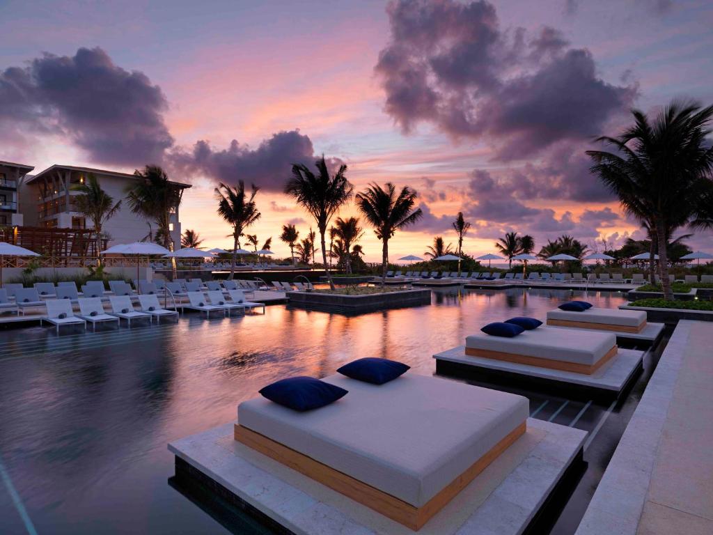 艾库玛尔Unico Hotel Riviera Maya Adults Only的一个带两张床和椅子的度假村和一个游泳池