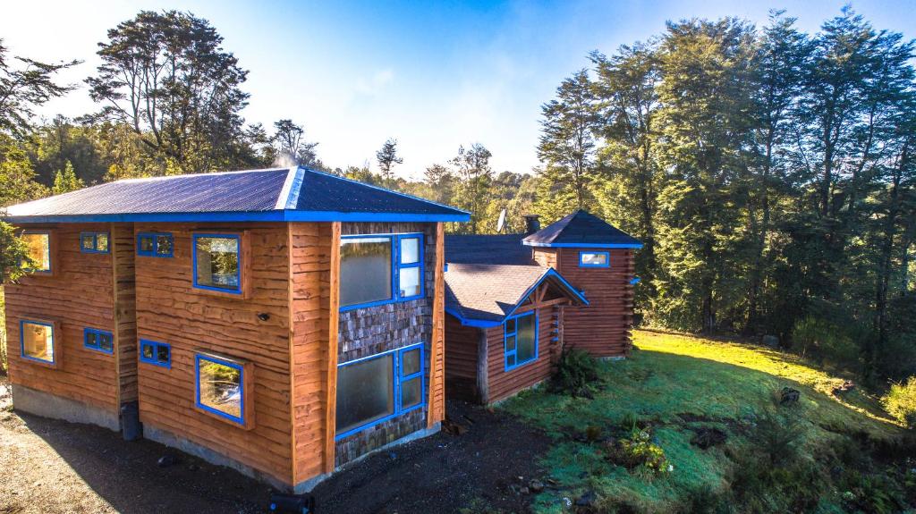 达卡卫Hostal Casa Bosque的庭院中带蓝色屋顶的小木屋