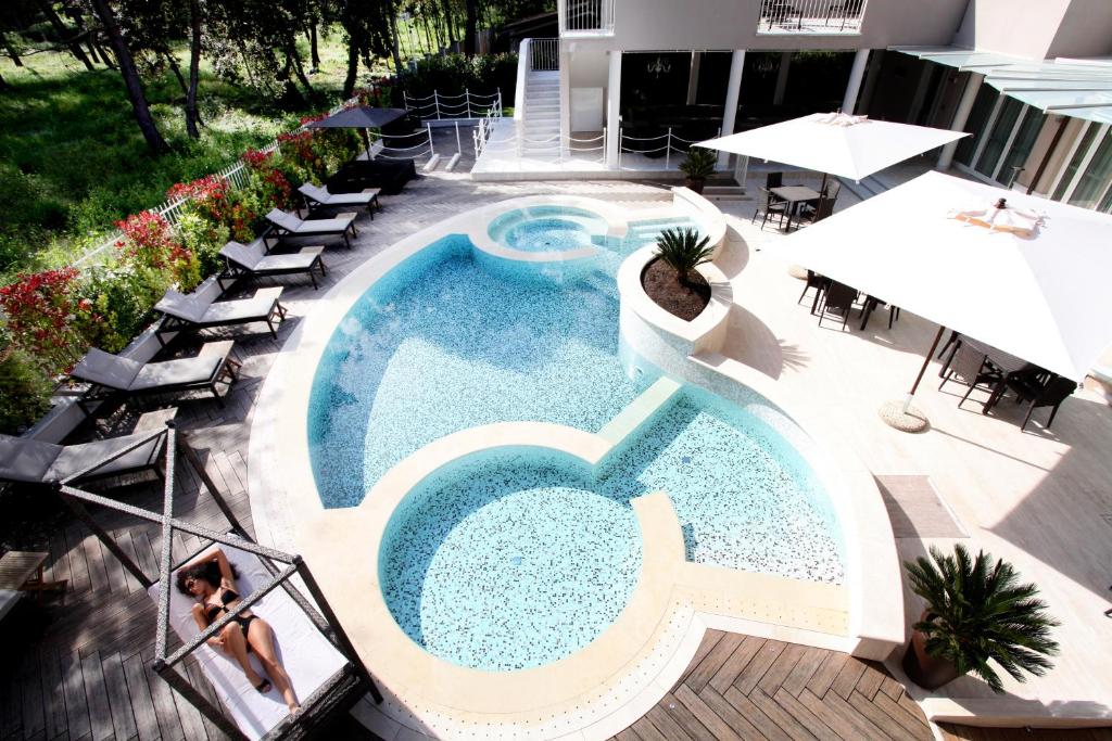 马里纳迪马萨斯特拉德拉维西利亚酒店的享有带椅子和遮阳伞的游泳池的上方景色