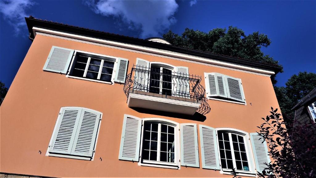 艾森纳赫Villa Terracotta的一座橙色的建筑,设有白色百叶窗和阳台