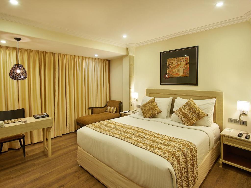 孟买The Shalimar Hotel, Kemps Corner的酒店客房设有一张大床和一张书桌。