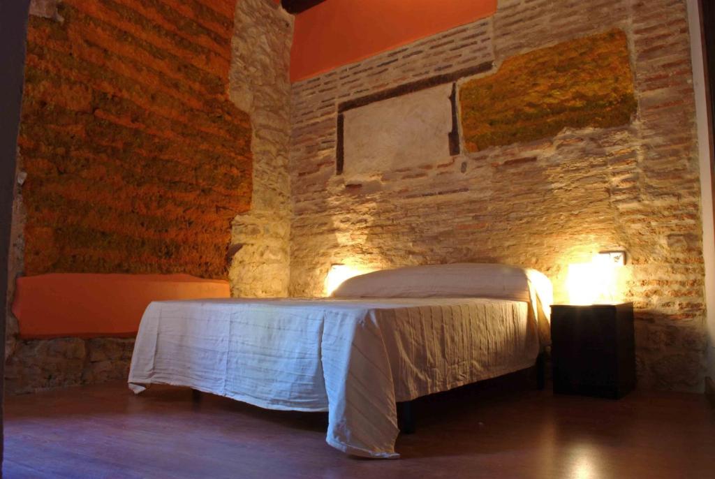 塞哥维亚自然广场旅馆的卧室配有砖墙内的床铺