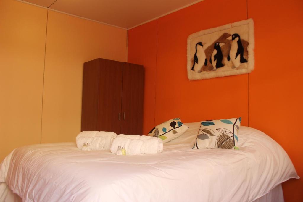 纳塔列斯港Hostal Baquedano的一间卧室配有一张白色的床和橙色的墙壁