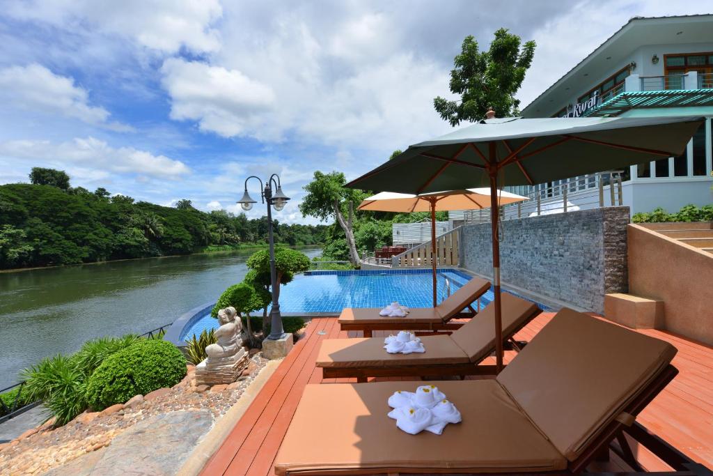 北碧奎河公主酒店的河畔带桌子和遮阳伞的游泳池