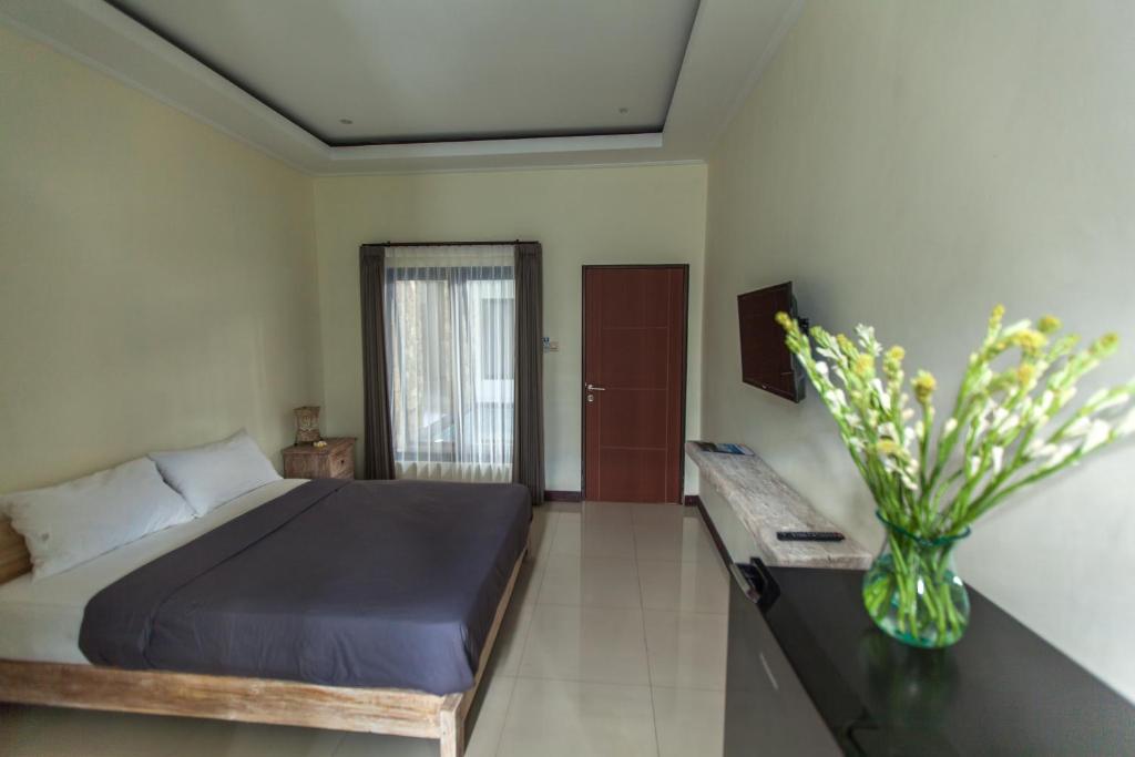 沙努尔乌玛巴古斯旅馆的一间卧室,配有一张床和花瓶