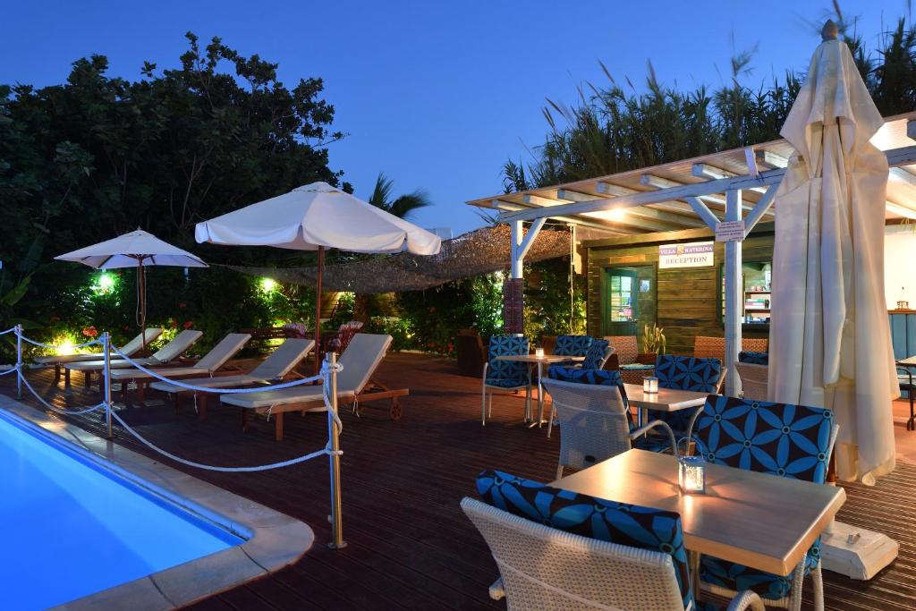 帕罗奇亚卡捷琳娜别墅酒店的游泳池旁带桌子和遮阳伞的天井