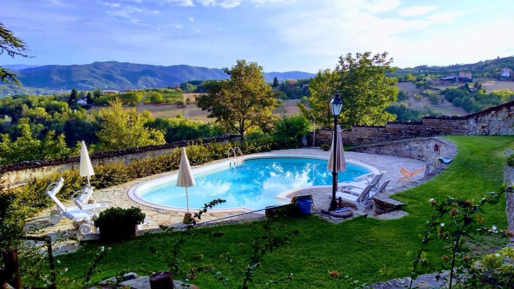奥瓦达格里兰诺城堡农家乐的庭院内的游泳池,配有椅子和遮阳伞