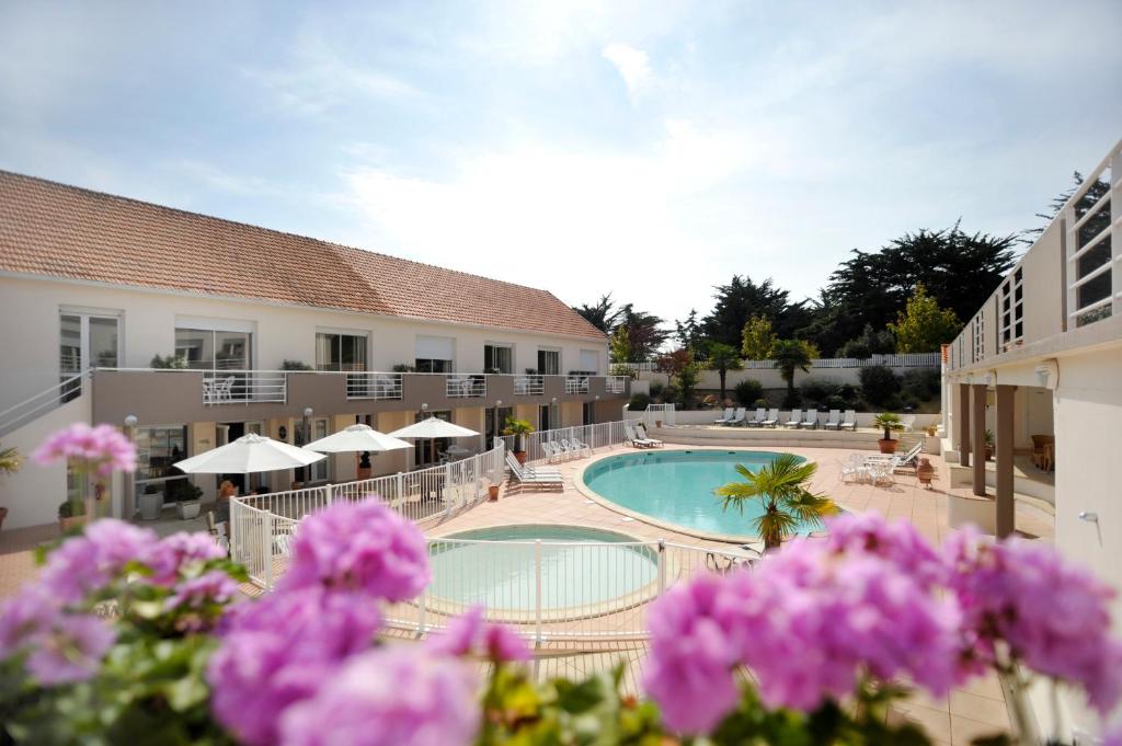 圣让-德蒙蓝色公寓酒店的一座带游泳池和紫色鲜花的酒店