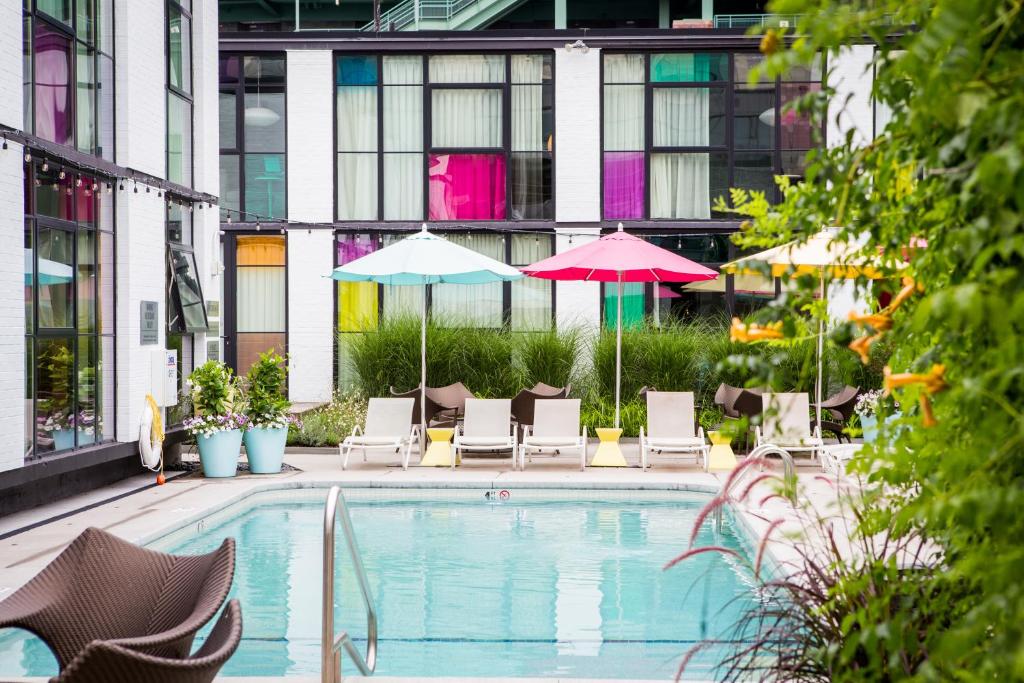 波士顿韦贝酒店的一座带椅子和遮阳伞的游泳池位于一座建筑旁边