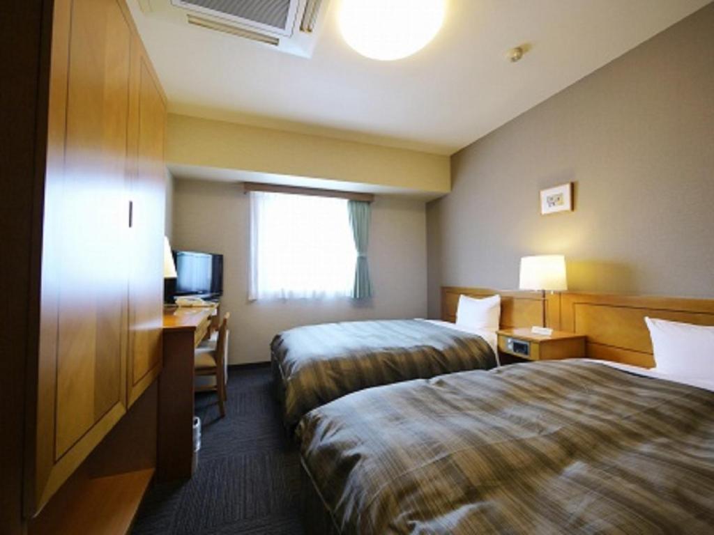 青森青森站前旅馆的酒店客房设有两张床、一张书桌和一个窗户。