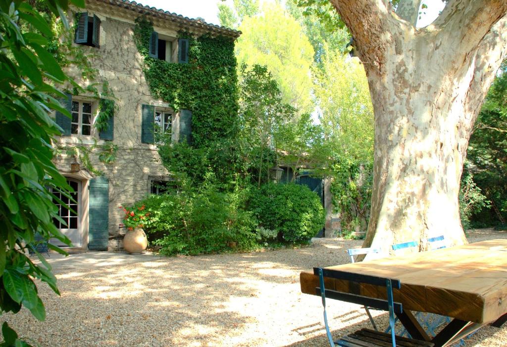 索尔格河畔利勒Maison d'hôtes Campagne-Baudeloup的坐在建筑物前的树下桌子