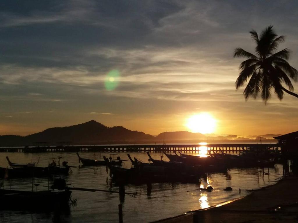 班柯木海滨旅馆的日落时分,棕榈树和水中的船只