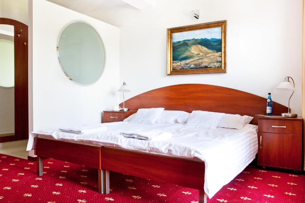 布科维纳-塔钱斯卡维拉公园旅馆的一间卧室配有一张大床和木制床头板