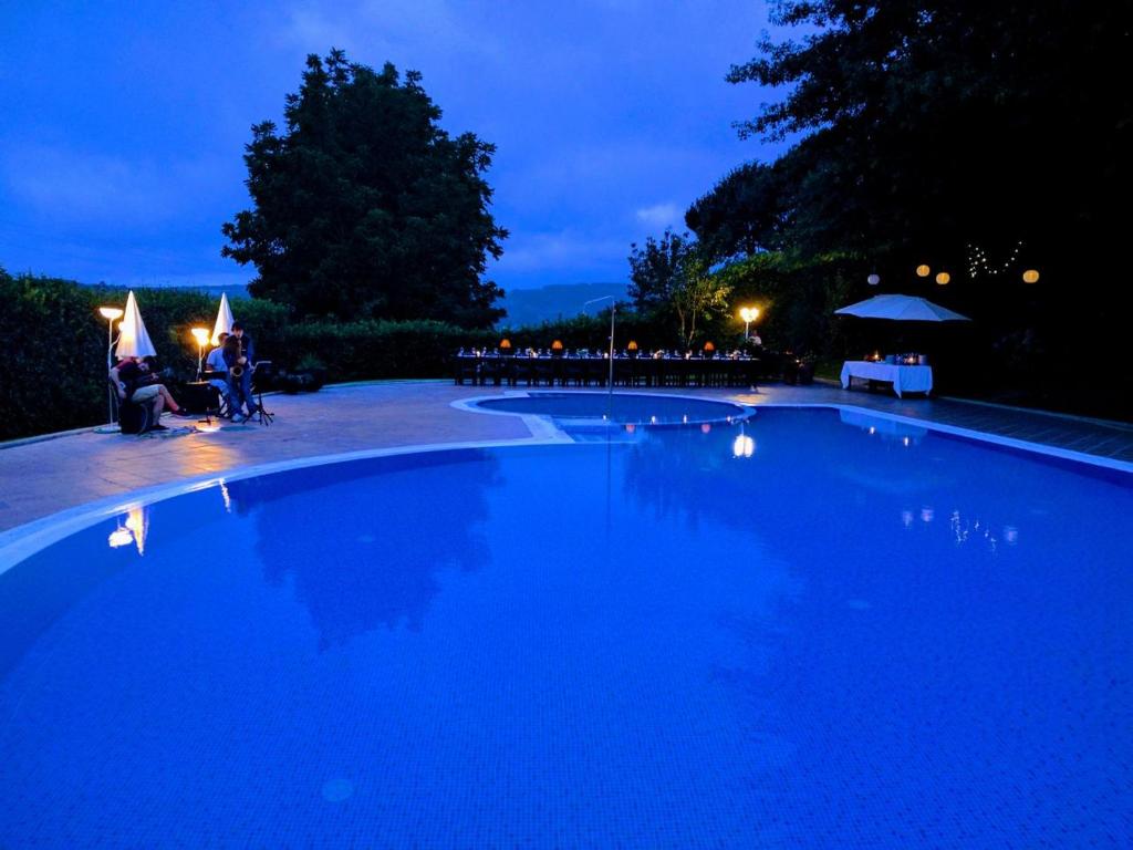拜昂阿尔蒙克莱维旅馆的一个大型蓝色游泳池,晚上有人围坐在泳池周围