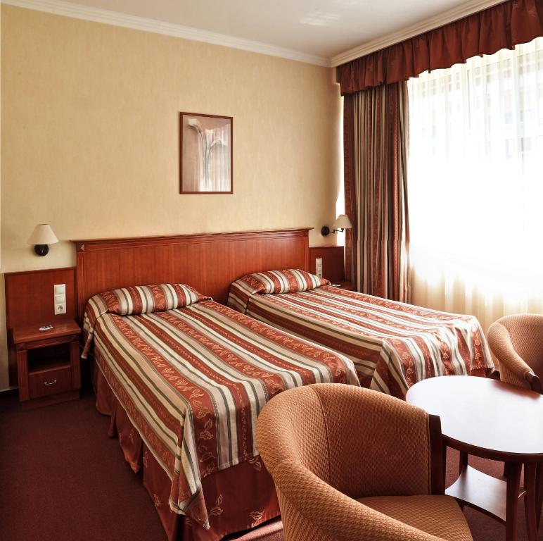 佩奇中央酒店的酒店客房设有两张床和一张桌子。