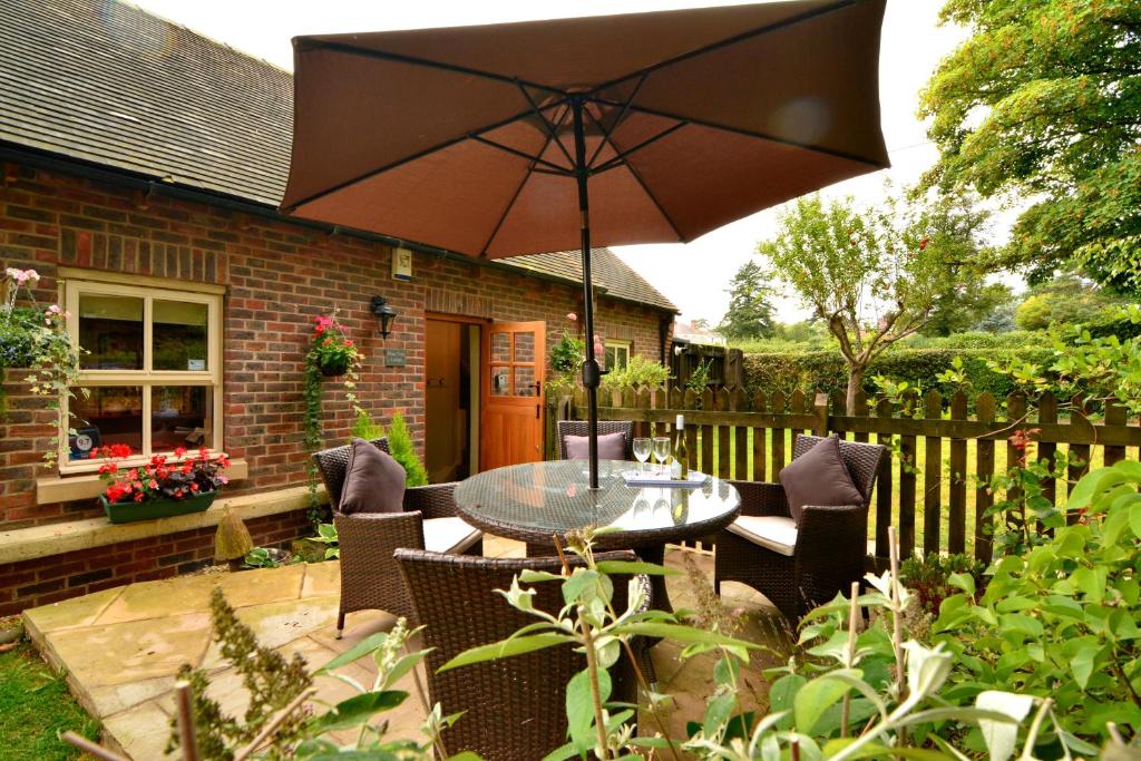 布里奇诺斯Pine Tree Lodge, Bridgnorth的庭院配有桌椅和遮阳伞。