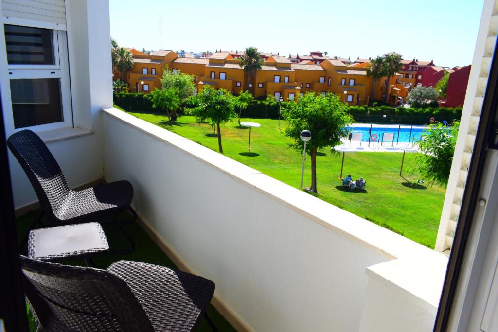 罗塔Apartamento Costa Ballena con WIFI的阳台配有两把椅子,享有游泳池的景色
