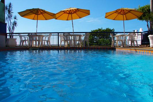 伊利利达麦美亚宾馆的一个带椅子和遮阳伞的游泳池以及一座池畔修道院