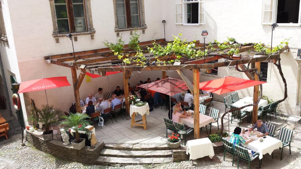 格拉茨Minihotel Graz的户外餐厅,有客人坐在桌子和遮阳伞下