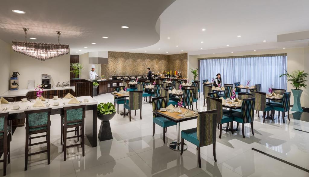 迪拜Savoy Crest Hotel Apartment - Bur Dubai的餐厅配有桌椅,背景人员