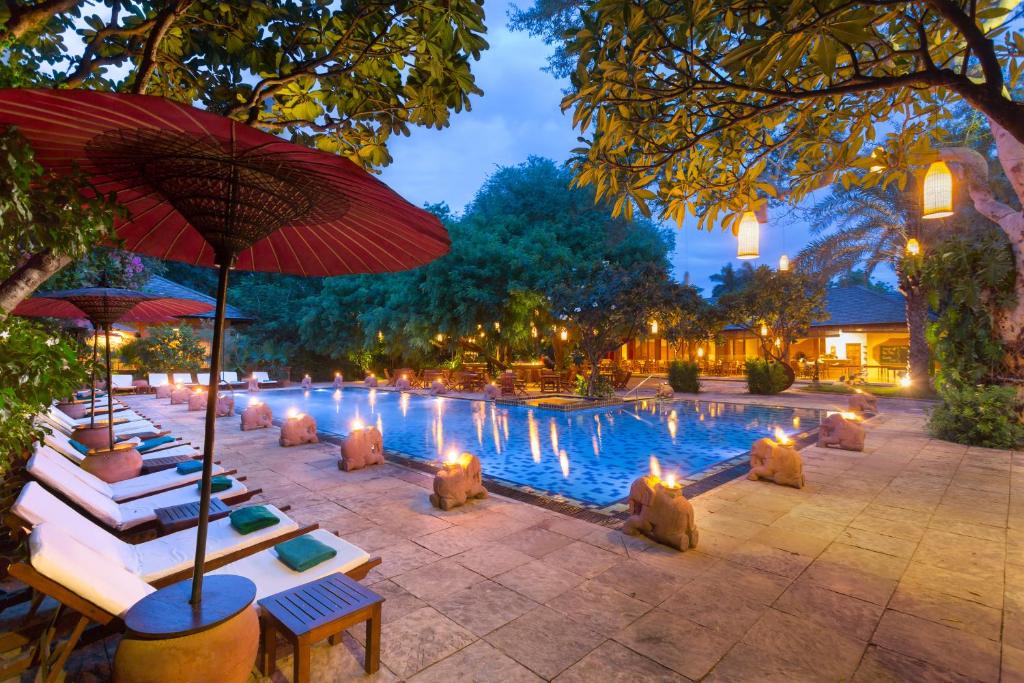 蒲甘泰拉巴之门酒店的游泳池前设有椅子和遮阳伞