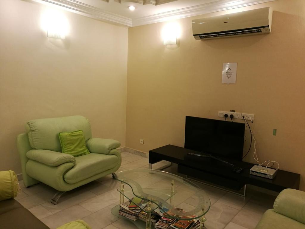 峇六拜槟城峇六拜维斯塔纳度假屋的客厅配有绿色椅子和电视